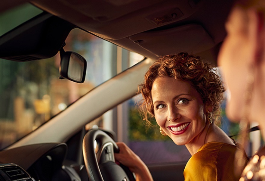 A female driver looking and smiling at female passenger in a Mitsubishi Mirage 