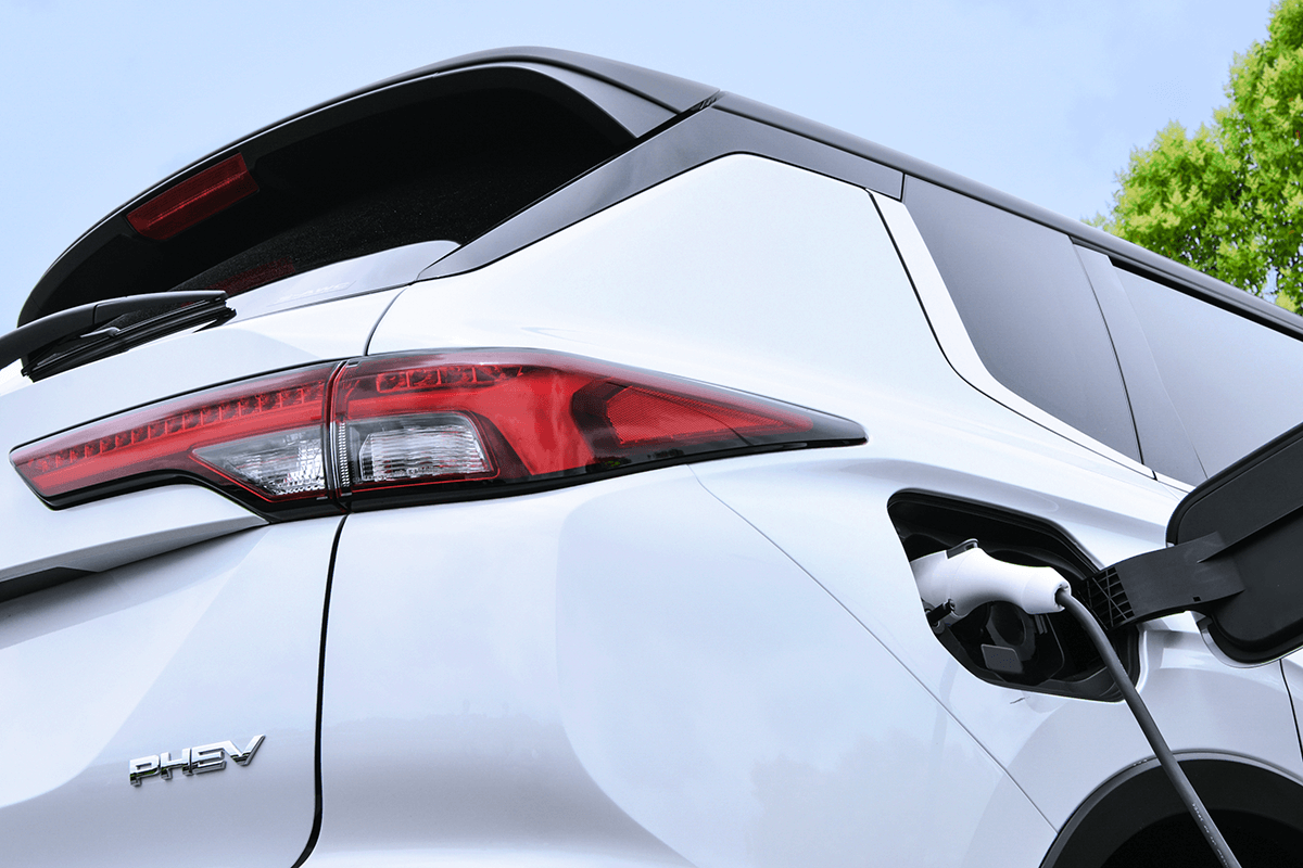 White PHEV Mitsubishi Outlander rear quarter shot plugged into EV charging port