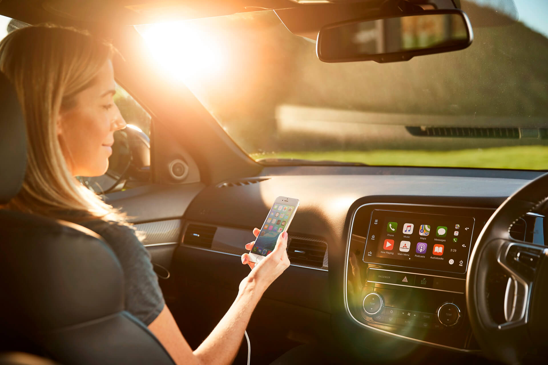 A woman using her iPhone with Apple CarPlay in a PHEV