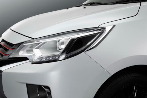A close up shot of front left headlight of a white Mitsubishi Mirage