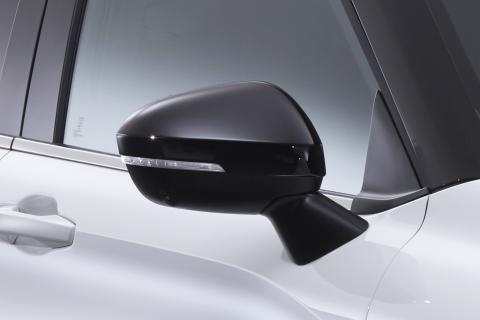 Wing mirror with a gloss black cover. Mounted on a white Mitsubishi Eclipse Cross with black frames around the window.