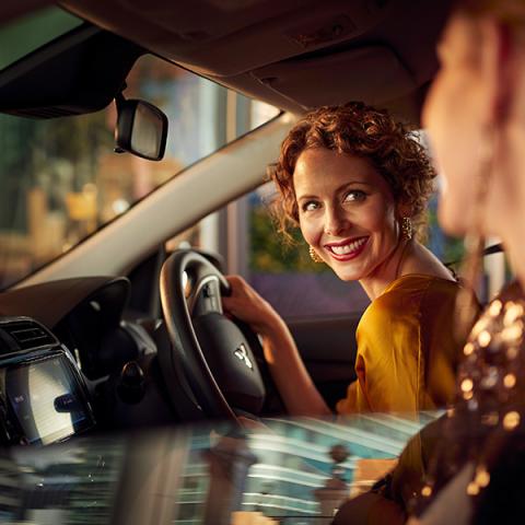 A female driver looking and smiling at female passenger in a Mitsubishi Mirage 