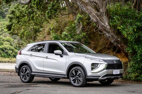 A silver Mitsubishi Eclipse Cross parked next to a cliff with a large tree growing out of it
